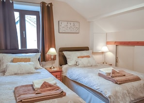 Habitación de hotel con dos camas, una ventana con cortinas, un cuadro colgado en la pared y lámparas de noche.