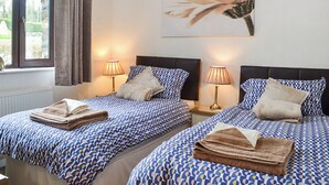 A hotel room with two beds, each with a patterned bedspread, bedside lamps, and a window with curtains. - 1 bedroom accommodation in Dolgellau (Dolgellau)