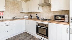 A kitchen with white cabinets, a gas stove, a microwave, and a sink.