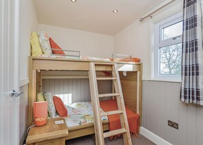 A bunk bed room with a ladder, a window with curtains, and a door. - Compact lodge finished to a high standard with one double and one with bunks. (Pickering)