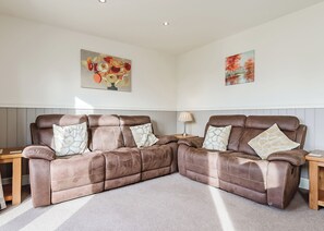 A brown leather sofa with patterned cushions, a lamp, and two paintings on the wall. - Compact lodge finished to a high standard with one double and one with bunks. (Pickering)