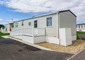 A single-story mobile home with a fenced deck, a small porch, and a garage.