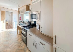 Una cocina moderna con estufa a gas, horno, microondas y electrodomésticos de acero inoxidable.