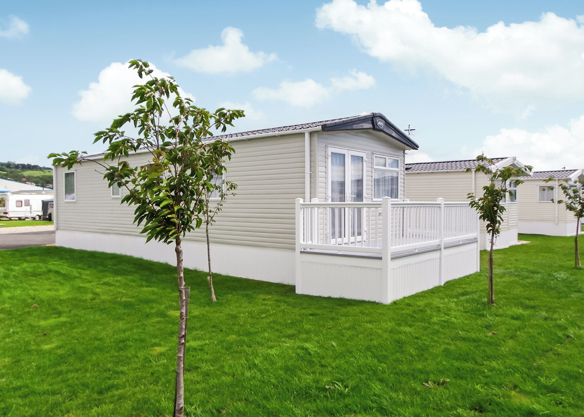 Ein Bungalow mit umzäunter Terrasse, umgeben von einem gepflegten Rasen.