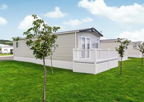 A single-story mobile home with a fenced deck, surrounded by a well-maintained lawn.