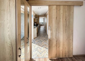 Interior de madera con piso de espiga, zona de cocina con armarios y una puerta corredera.