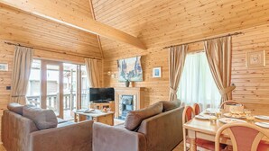 Un acogedor interior de cabaña con sofá, televisor, chimenea y comedor.
