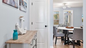 A dining area with a round table and chairs, a wooden sideboard, and a white door. - 2 Bikes! Steps to the Pool! Bike to Beach! 1st Fl Condo! - Silk Beach on 30A at Topsail Village (Santa Rosa Beach)