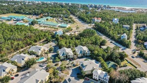An aerial view of a residential area with houses, a swimming pool, and a beach in the background. - 2 Bikes! Steps to the Pool! Bike to Beach! 1st Fl Condo! - Silk Beach on 30A at Topsail Village (Santa Rosa Beach)