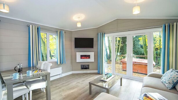 A modern living room with a fireplace, a dining area, and a sofa with a magazine. - 2 bedroom accommodation in Welburn (Welburn)