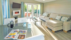 A modern living room with a sofa, coffee table, and a flat-screen TV. - 2 bedroom accommodation in Welburn (Welburn)