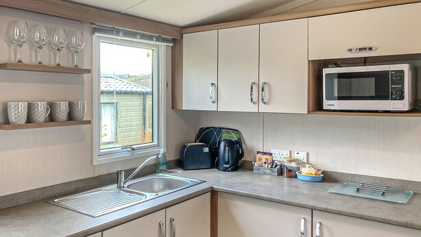 A compact kitchen with a sink, microwave, and cabinets.