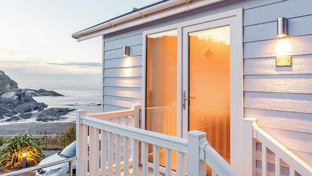 Una casa costanera amb un balcó, una porta corredissa de vidre i vista a l'oceà.