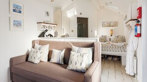 Habitació d'hotel moderna amb sofà, llit, bany i petita cuina.