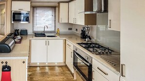Eine kleine Küche mit Mikrowelle, Toaster, Spüle, Herd, Backofen und Schränken.
