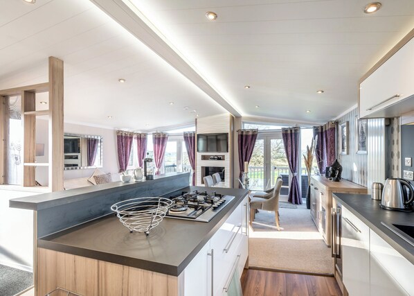 A modern kitchen with a central island, built-in appliances, and a view to the outside.