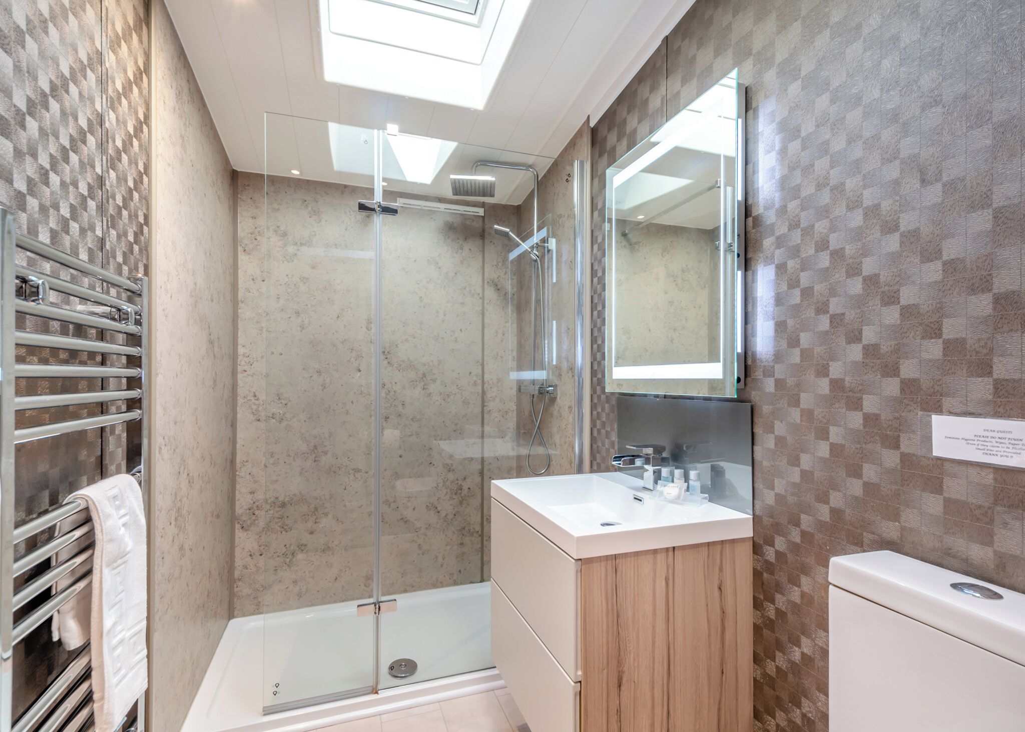 Une salle de bain moderne avec une douche à parois de verre, un meuble-lavabo avec un miroir et un porte-serviettes.