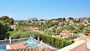 Zona residencial con vistas a una cordillera, piscina con sillas de descanso y un jardín bien cuidado.