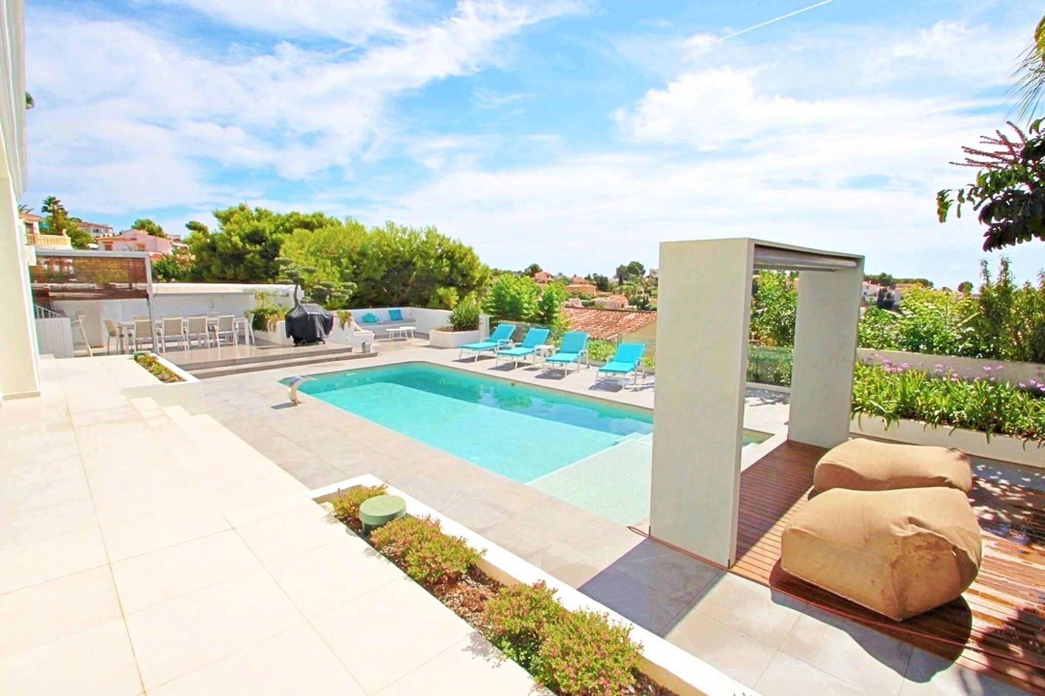 A swimming pool with lounge chairs, a barbecue area, and a pergola.