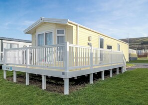 Una casa móvil con un porche delantero con ventanas y una terraza blanca.