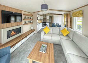 A modern RV interior with a living area, kitchen, and dining space.