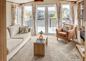A living room with a sofa, armchair, coffee table, and curtains. - 2 bedroom accommodation in Laurenkirk (Laurenkirk)