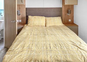 A neatly made bed with a patterned bedspread, a wooden headboard, and bedside lamps. - 2 bedroom accommodation in Laurenkirk (Laurenkirk)