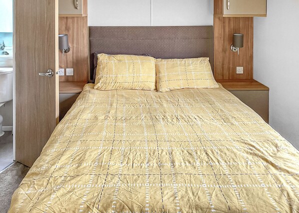 Un lit bien fait, avec une couvre-lit à motifs, une tête de lit en bois et des lampes de chevet.