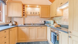 Una cocina con gabinetes de madera, un fregadero, una estufa y un microondas.