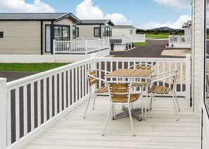 Eine Terrasse mit Gartenmöbeln, weißen Geländern und Blick auf Mobilheime.
