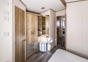 Ein Schlafzimmer mit Holzschrank, Bett und kleinem Fenster.