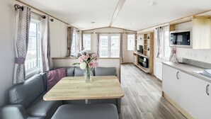 Een modern RV-interieur met een eethoek, zitplaatsen, een keuken met een magnetron en een televisie.