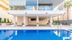 Um edifício moderno com piscina, varandas e vista para palmeiras.