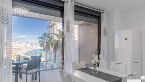 Quarto moderno com varanda vista para a praia e paisagem urbana.