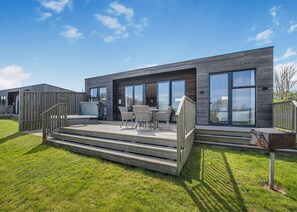 A modern building with a deck, outdoor seating, and large windows.