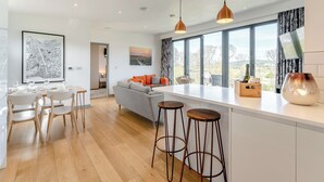 Una cocina moderna con una isla grande, taburetes de bar y un comedor con sillas y una mesa.