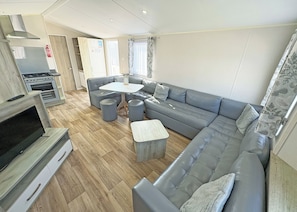 Ein modernes Wohnzimmer mit einem grauen Sofa, einem kleinen Tisch und einem Fernseher.