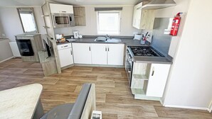 Een moderne keuken met witte kasten, een gasfornuis, een magnetron en een inbouwoven.