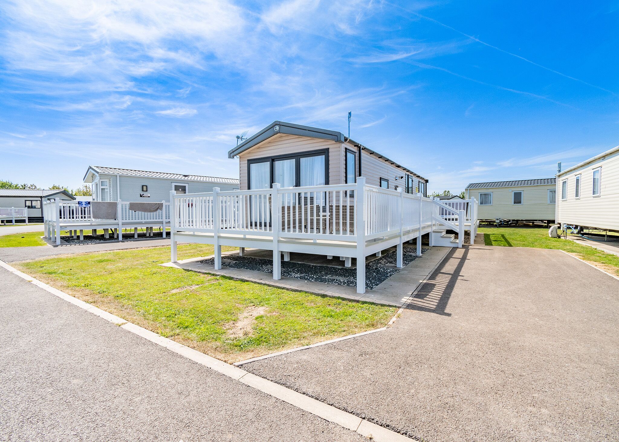 A mobile home with a deck and a covered porch, surrounded by other similar homes.