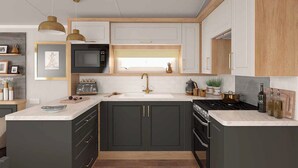 A modern kitchen with dark cabinets, a microwave, stove, and a sink.