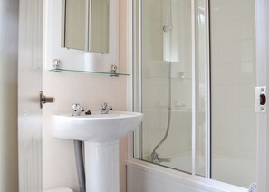 A bathroom with a white sink, a glass shower enclosure, and a mirror above the sink. - Traditional yet comfortable caravan with one double and two twins. (Dolgellau)