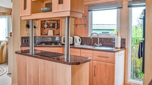 Une cuisine moderne avec des meubles en bois, une cuisinière encastrée, un évier et une fenêtre avec des stores.