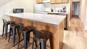 Een moderne keuken met een groot eiland, houten kastjes en barstoelen.