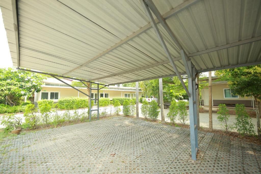 A covered outdoor area with a tiled floor, metal roof, and a view of residential buildings in the background.