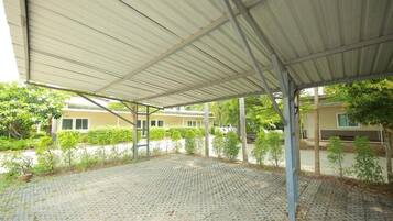 A covered outdoor area with a tiled floor, metal roof, and a view of residential buildings in the background.