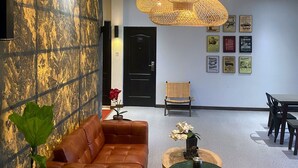 A modern lobby with a leather sofa, a round table, and a large woven light fixture. - Hotel Pantes Candi Semarang (Semarang)