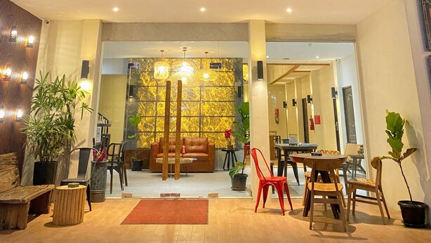 A modern hotel lobby with a glass entrance, a seating area with a sofa and chairs, and a decorative wall with a patterned design. - Hotel Pantes Candi Semarang (Semarang)