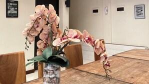 A conference room with a wooden table, a vase with orchids, and a wall with motivational posters. - Hotel Pantes Candi Semarang (Semarang)