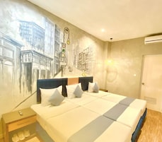 A hotel room with a large bed, a nightstand, and a wall mural of a cityscape.