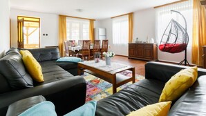 A modern living room with a sofa set, a hanging chair, and a dining area with chairs and a table. - Vacation home Nimrod by Interhome (Balatonfenyves)